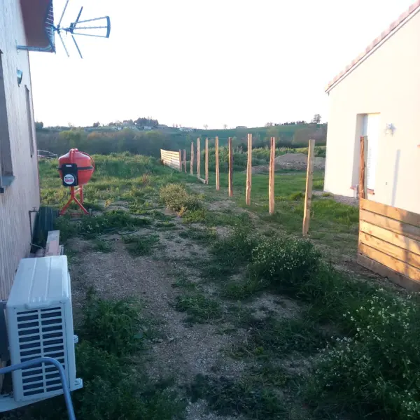 Clôture en bois en cours de pose par sola dans un jardin entre deux maisons à limoux