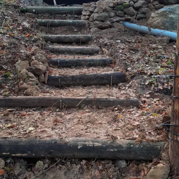 Escalier rustique en rondins dans un talus boisé aménagé par sola près de limoux